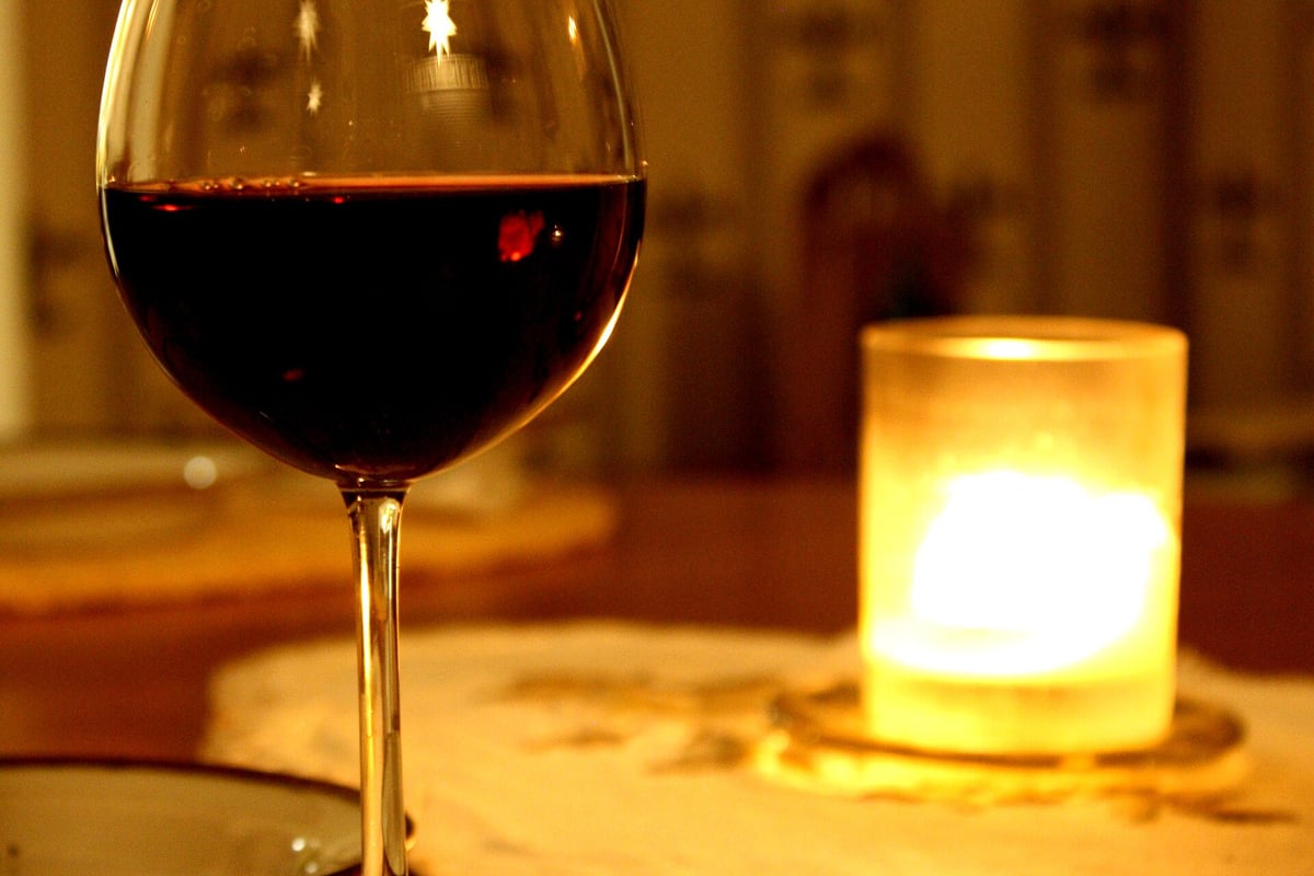 Een glas rode wijn op tafel bij kaarslicht in de avond