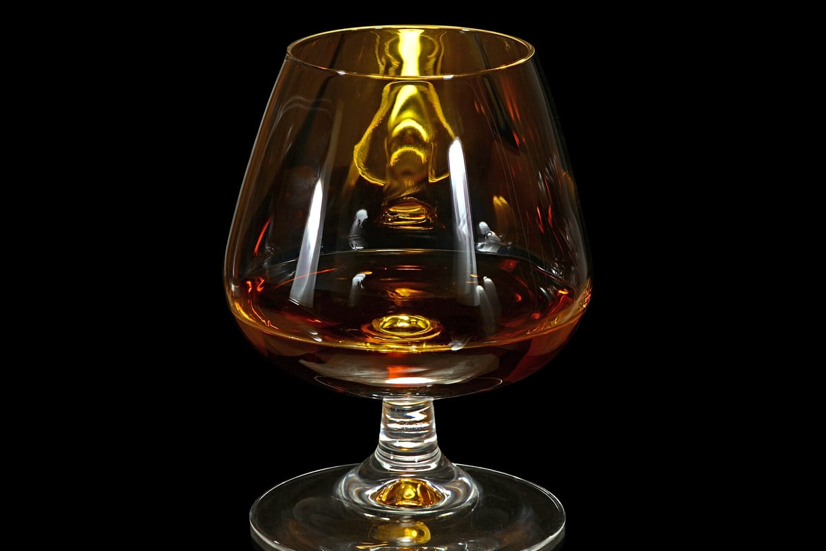 Glas cognac doorschenen met warm licht tegen een donkere achtergrond